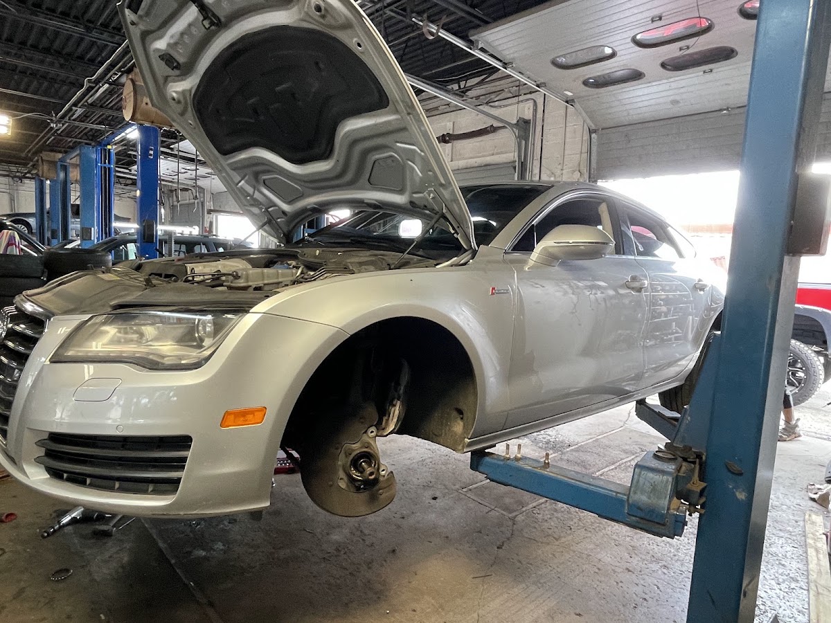 Inside Columbus Quality Auto Care's shop — a car raised on a two-post lift with the hood open for service